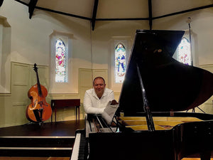 James Tait standing by the piano at Coquetdale Music Trust